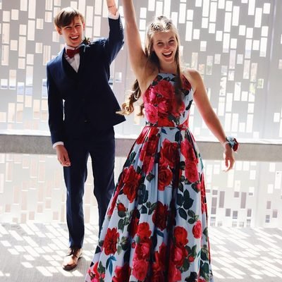 Prom 2019 Dress Ideas from a girl in a long floral print prom dress being twirled by date in tux