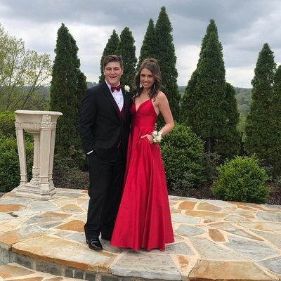 Prom 2019 Dress Ideas from a girl in a long red prom dress smiling with her date in tux